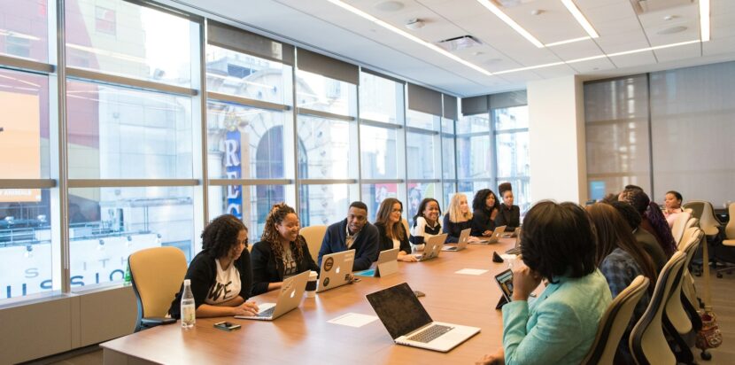 group of people sitting beside rectangular wooden table with laptops